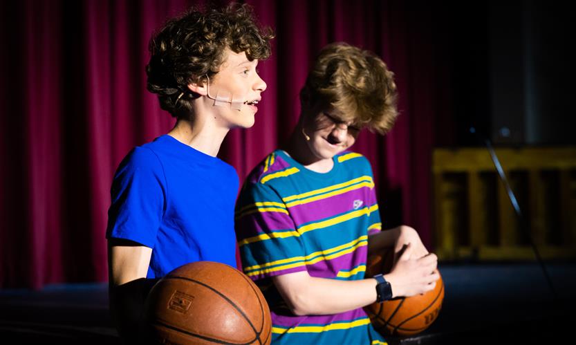 Two cast members talk just off stage